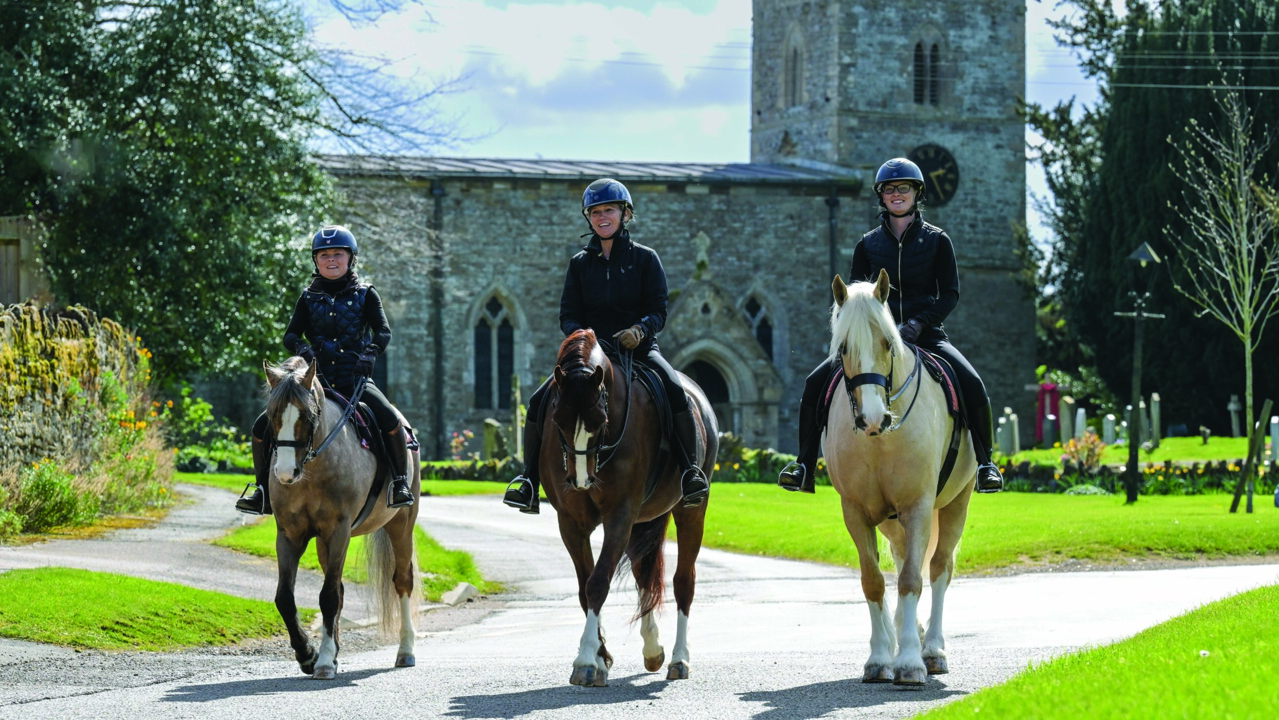 (L to R) Cadlanvalley Royal Bronze and Alice Tomlinson, centre Cadlanvalley Eldorado and Katy, and Garthfach Classic Addition and Kimberley Bates hack through the village of Hardwick in Northamptonshire in April 2026.