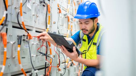 An electrical worker performs tests inside a distribution center.