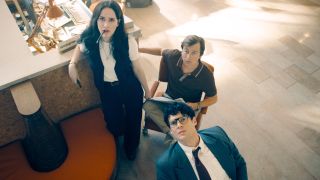 Rachel Brosnahan Skyler Gisondo and David Corenswet watch a report intently in the newsroom in Superman.