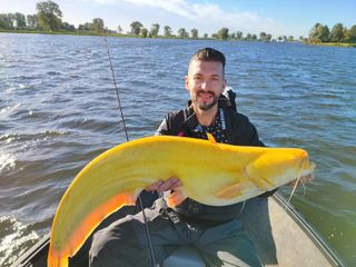 Fisherman Martin Glatz poses with the banana-yellow catfish before releasing it back into the water.