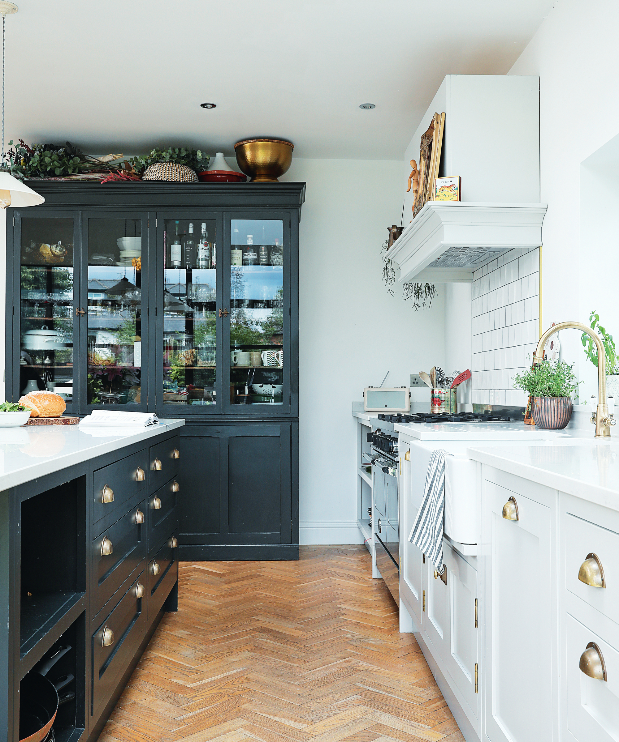 kitchen with blue and white painted cabinets, island, floor to ceiling units, and herringbone wooden floor