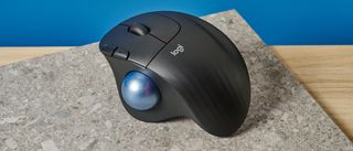 A black Logitech Ergo M575 ergonomic mouse with a teal trackball on the left side