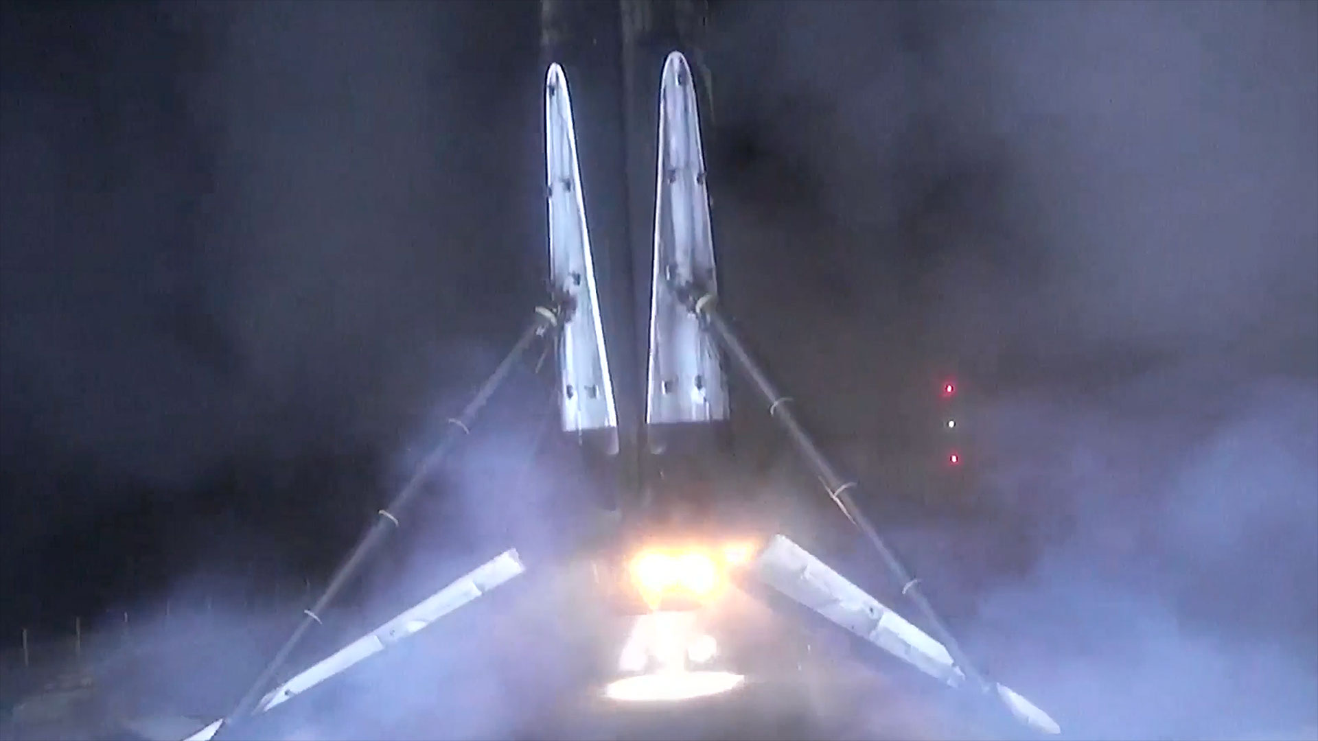 the first stage of a rocket stands atop its four legs after landing on an ocean-based plaform