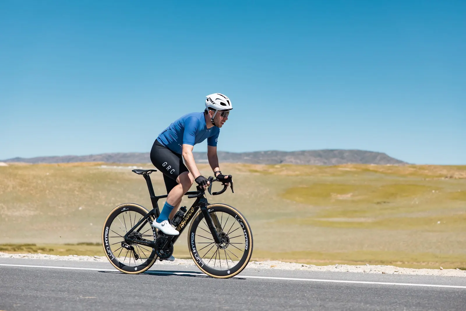 A man riding a Winspace road bike in front of green fields 