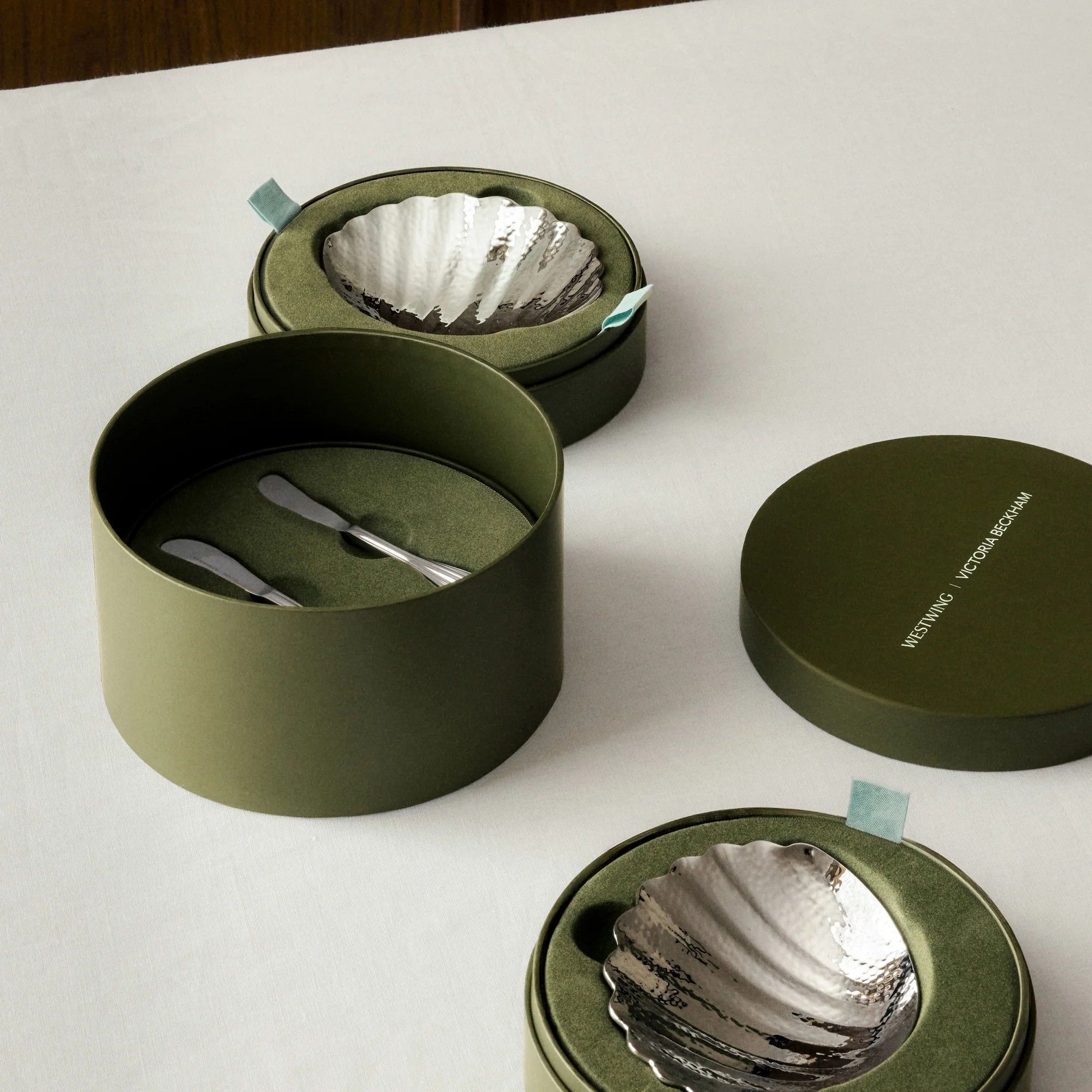 The Isla Stainless Steel Butter Dishes and butter knives from Victoria Beckham's collection with Westwing packed in green branded boxes