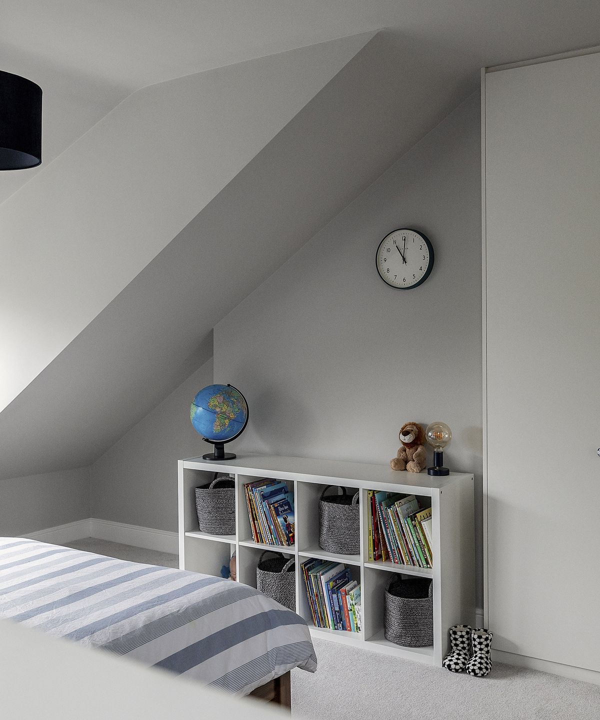 Shelving in a child's bedroom with grey walls and a clock