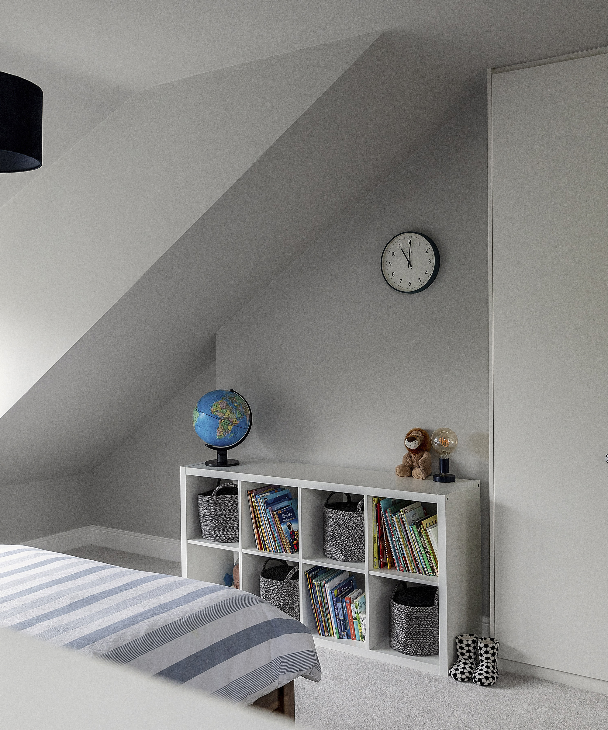 Shelving in a child's bedroom with grey walls and a clock