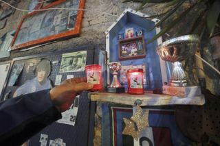 A man in Naples places a candle of St Padre Pio in a makeshift shrine to Diego Maradona