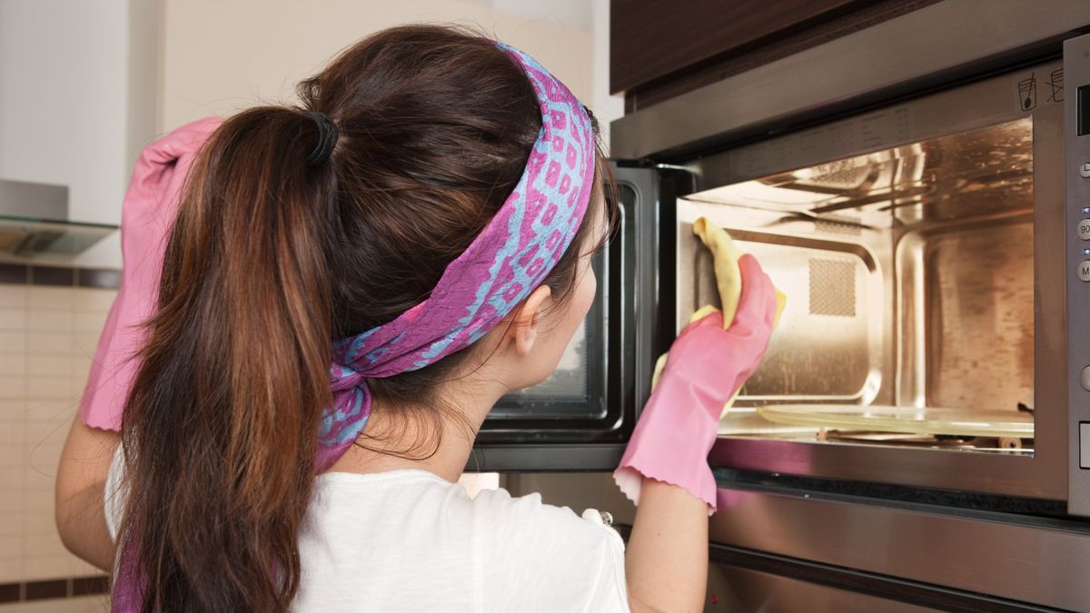 How to clean a microwave: Woman cleaning inside of microwave