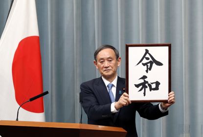 Japan's Chief Cabinet Secretary Yoshihide Suga announces the name of the new Imperial era by holding up a framed calligraphy parchment revealing the moniker: "Reiwa."