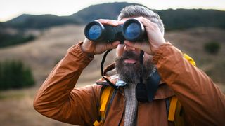 Man holding one of the best rangefinder binoculars in open hilly terrain