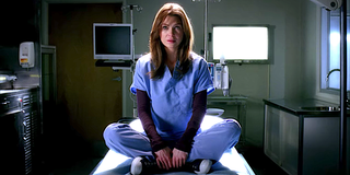 Grey's Anatomy Meredith Grey sits on a gurney in a dark hospital room.