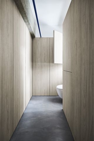 Bathroom in Alex's apartment in Singapore with wooden walls and grey floor