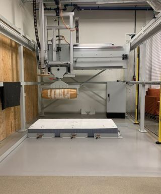 The test equipment in the IKEA Test Lab; a rolling pin lowered onto a mattress.