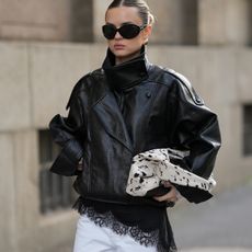 Romina Meier in an oversized black leather jacket, asymmetrical lace-trim dress, and white denim. 