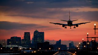 An airplane landing at London City Airport at sunset