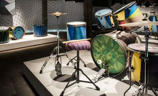 A colourful drum set. The drums have a geometrical fabric and paint on them.