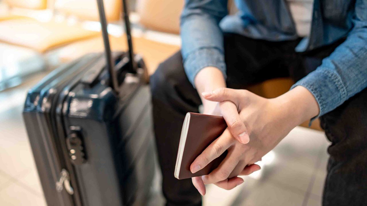 A suitcase and a person&#039;s hands folded nearby