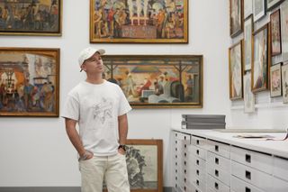 A portrait of Daniel Arsham in an art archive at Kohler, with paintings on the walls around him