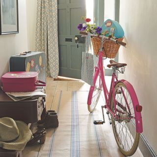 pink bike in hallway with suitcases and open door