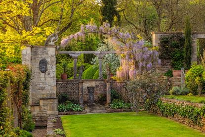 One of the total of nine terraces at Iford, with a small paved court with wrought-iron work, a panel of arms and pieces from Peto's collection of antiquities. Credit: Clive Nichols