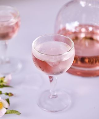 Close up of glass of rose, carafe in background, white tablecloth