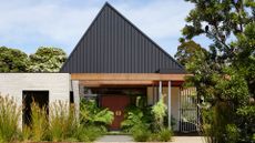 A home exterior with a triangular roof, a garden pathway and an orange front door