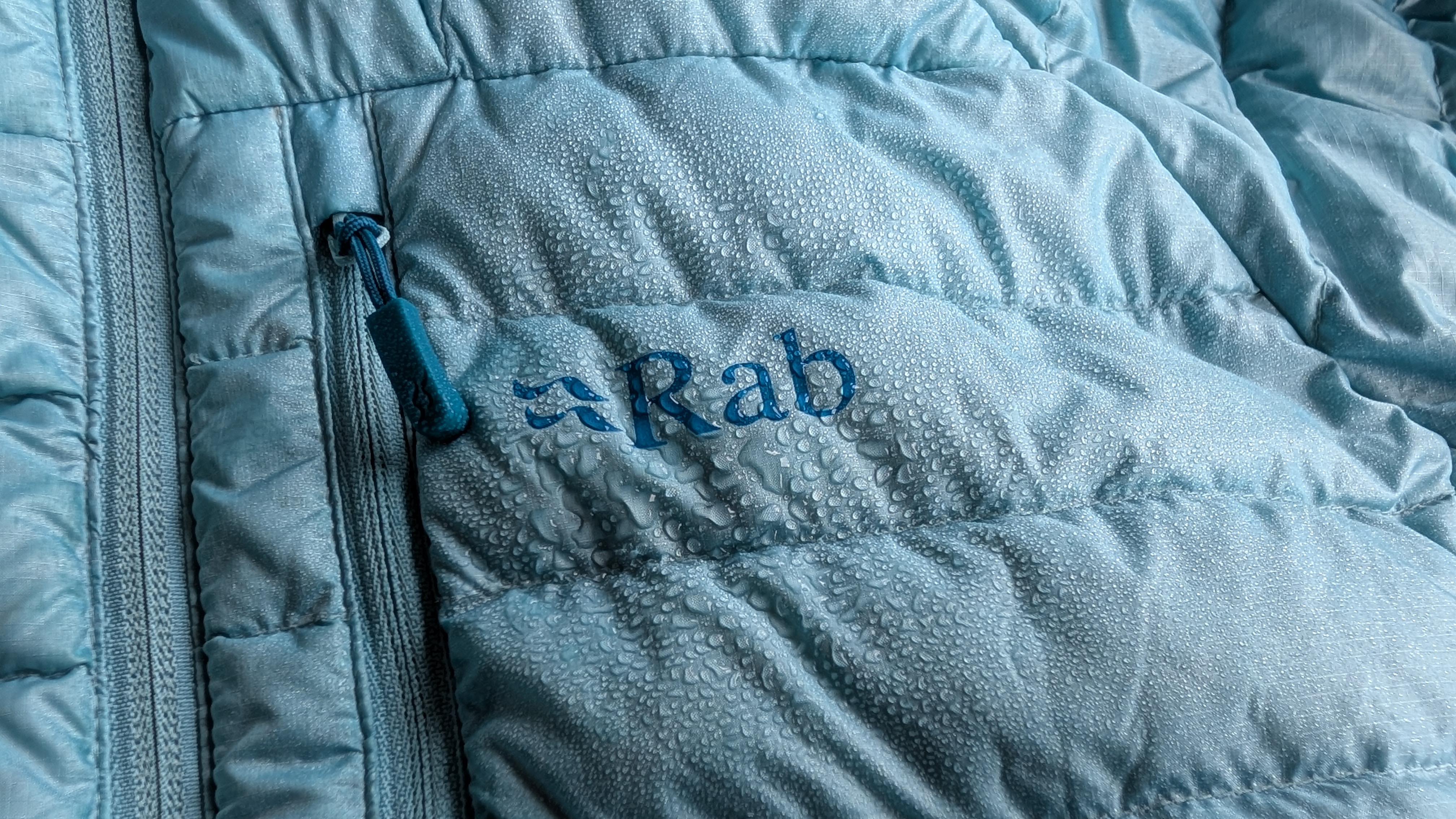 A close up showing water beading on a blue Rab down jacket