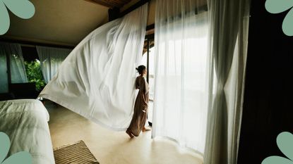 A woman looking out of the window in a luxury hotel room, an image used to illustrate woman&home's article on 'how to get the best hotel deals'