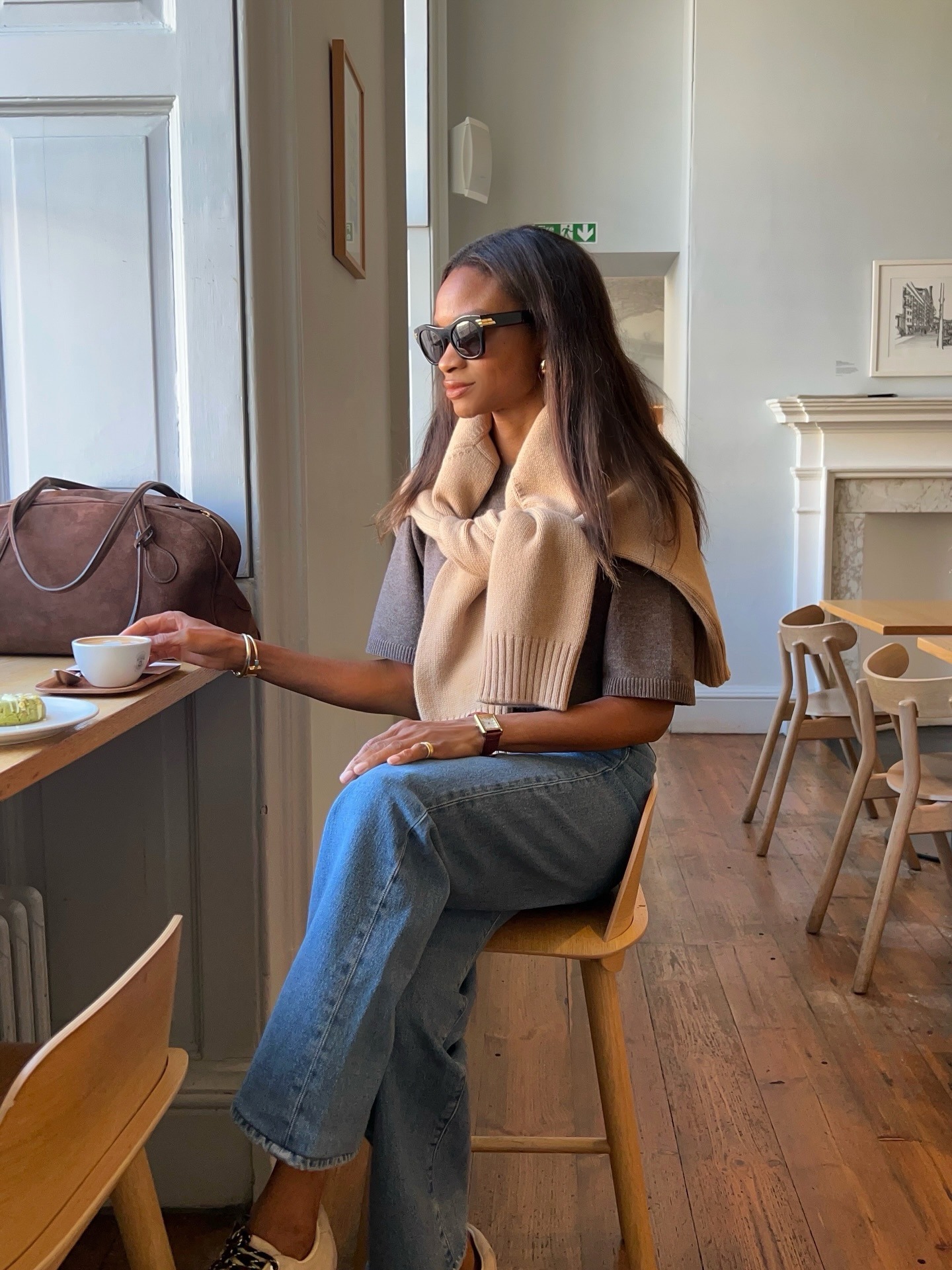 Woman wears beige jumper, grey top, blue jeans