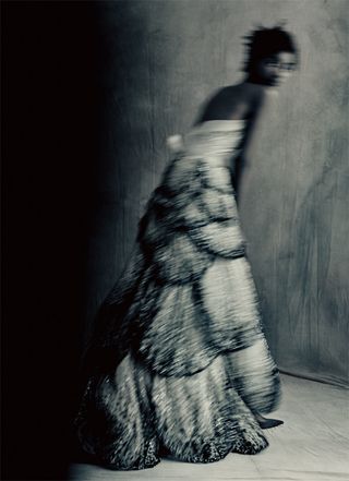 Black and white blurred image of a woman wearing a layered ballgown