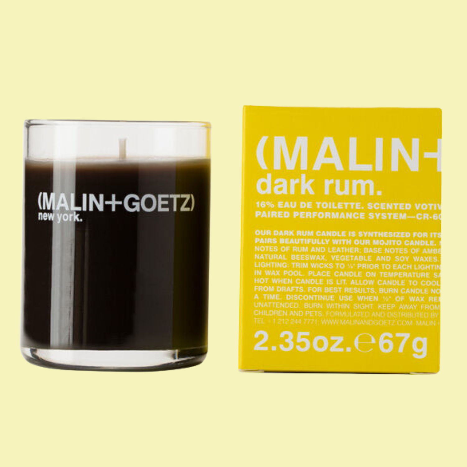 A glass candle and a yellow box against a butter yellow backdrop