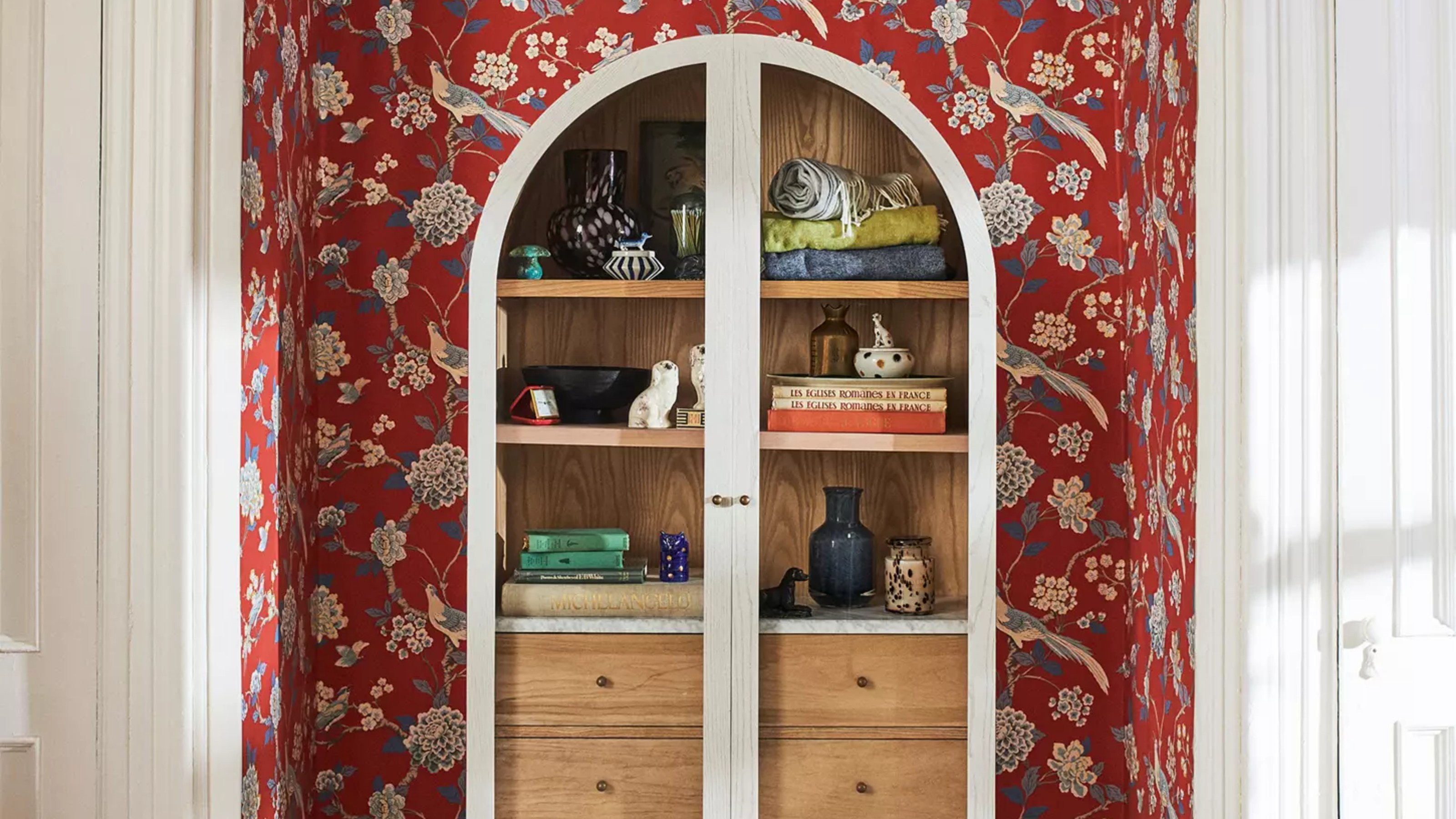 Anthropologie Fern Ash Wood Storage Cabinet in a hallway set against a red floral wallpaper