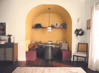 Breakfast nook with arch painted yellow, maroon and off-white.