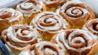 Cinnamon Rolls that have been freshly baked and topped with sweetened cream cheese