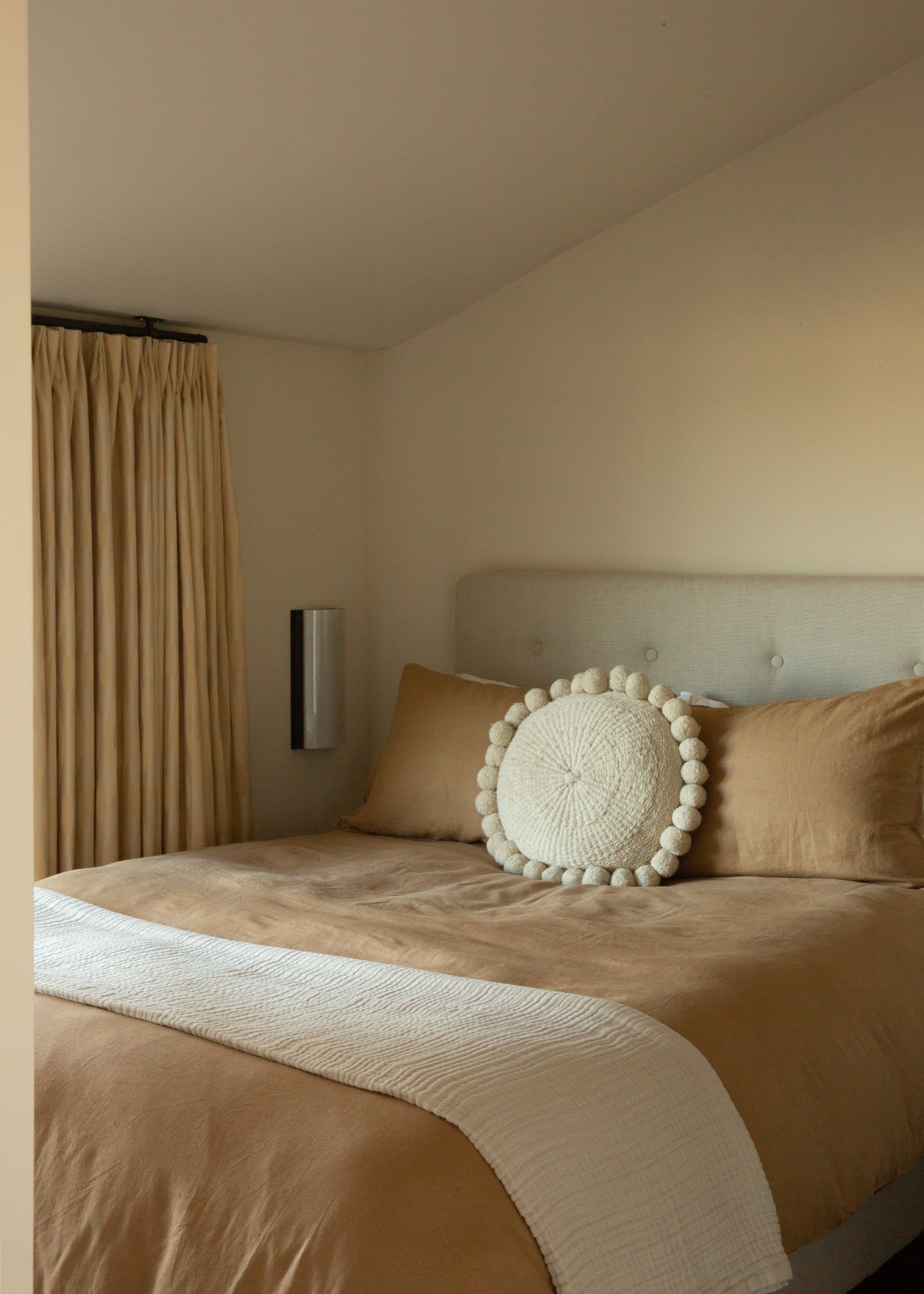 A white bedroom with a beige bedscape