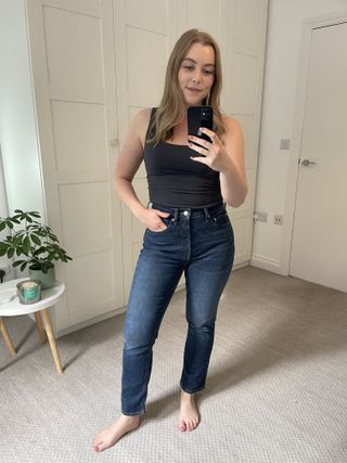 Woman wears grey tank top and blue skinny jeans