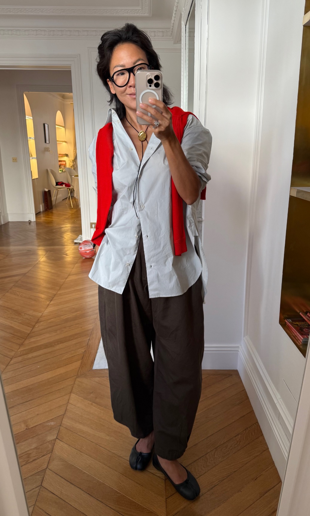 Irene Kim wearing a button-down shirt, a sweater, pants, and flats