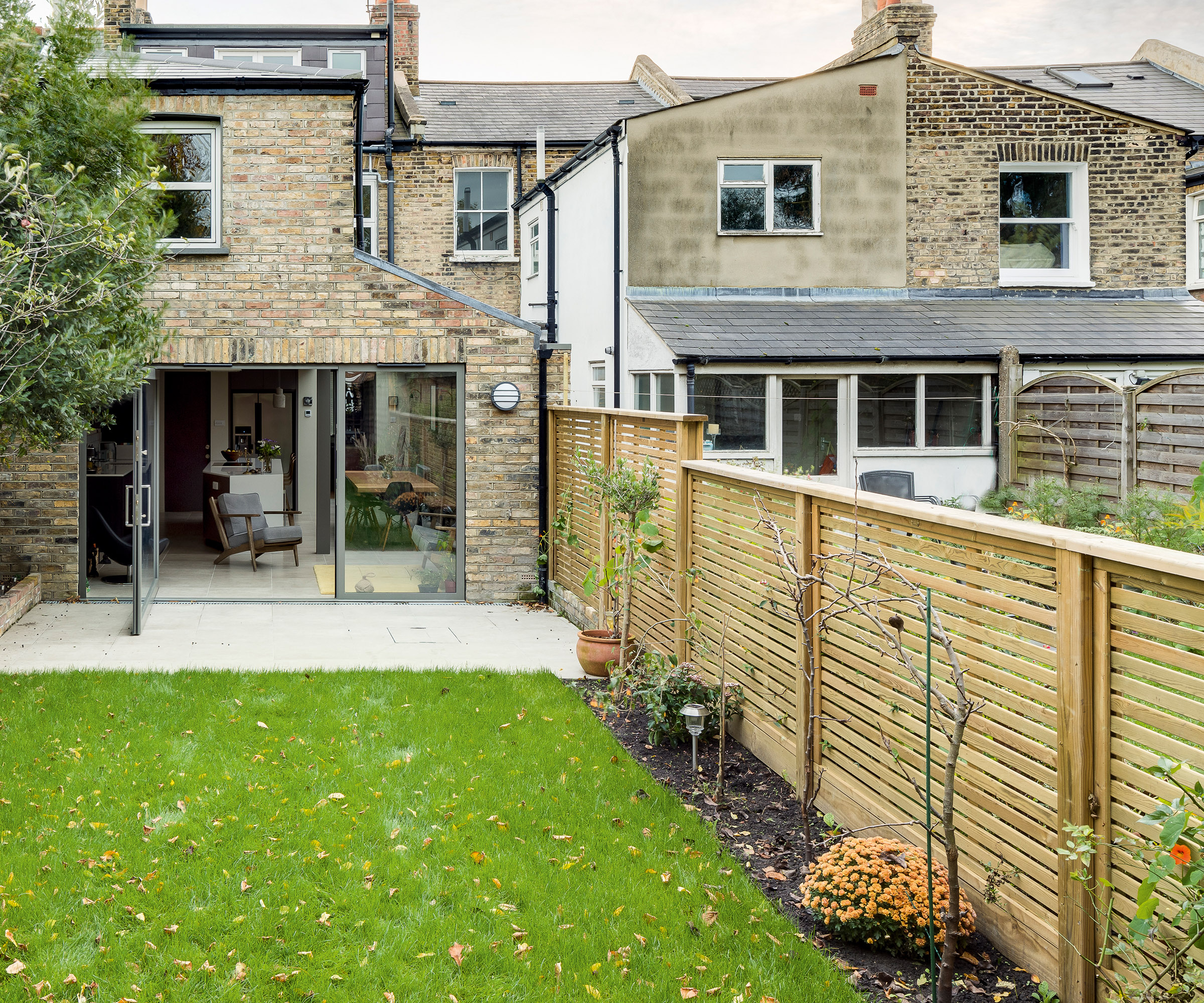 A newly. installed wooden boundary fence with horizontal slats and wooden fence posts