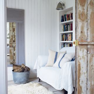 wood panelled snug with sofa, bookshelf and log bucket