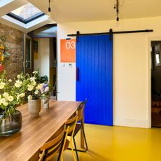 Neutral kitchen-dining room with yellow floor and bright blue stable door