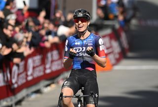 Demi Vollering sits up to salute after winning Strade Bianche, her black shorts covered in dust and salt