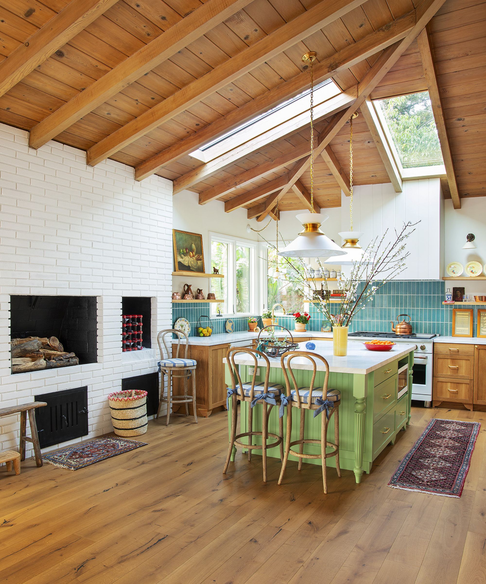 A ranch style meets mid-century kitchen with wood vaulted ceilings, wood cabinets, blue backsplash tiles, and a green island