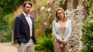 Kenny Doughty as Chris and Sally Bretton as Zoe stand in a garden looking pensive in The Au Pair.