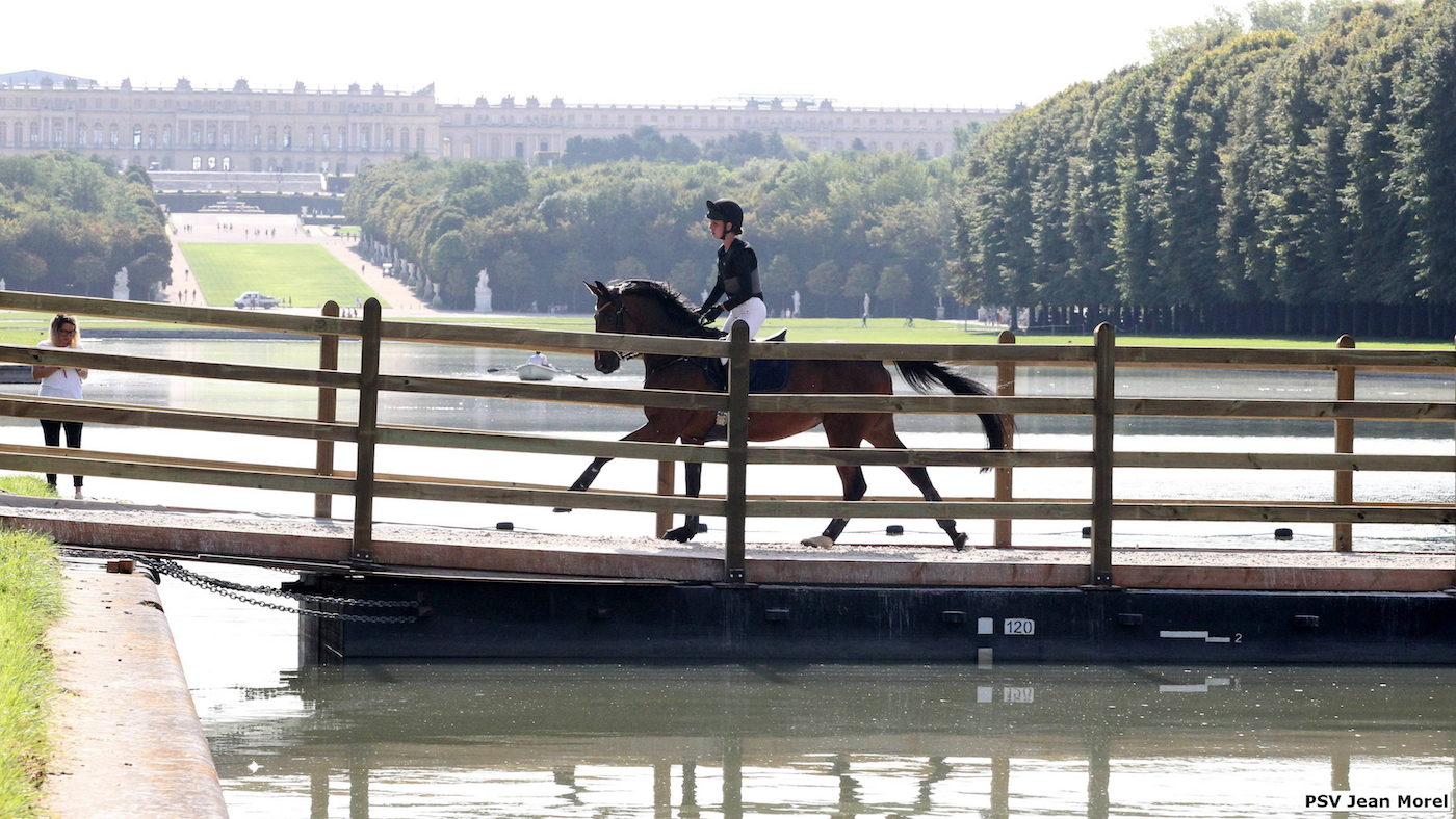A horse and rider on the pontoon crossing over the Grand Canal at Versailles with the palace in the background, during the cross-country test for the Paris 2024 Olympics.