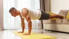 Man at home doing a deficit push-up with both feet on the couch