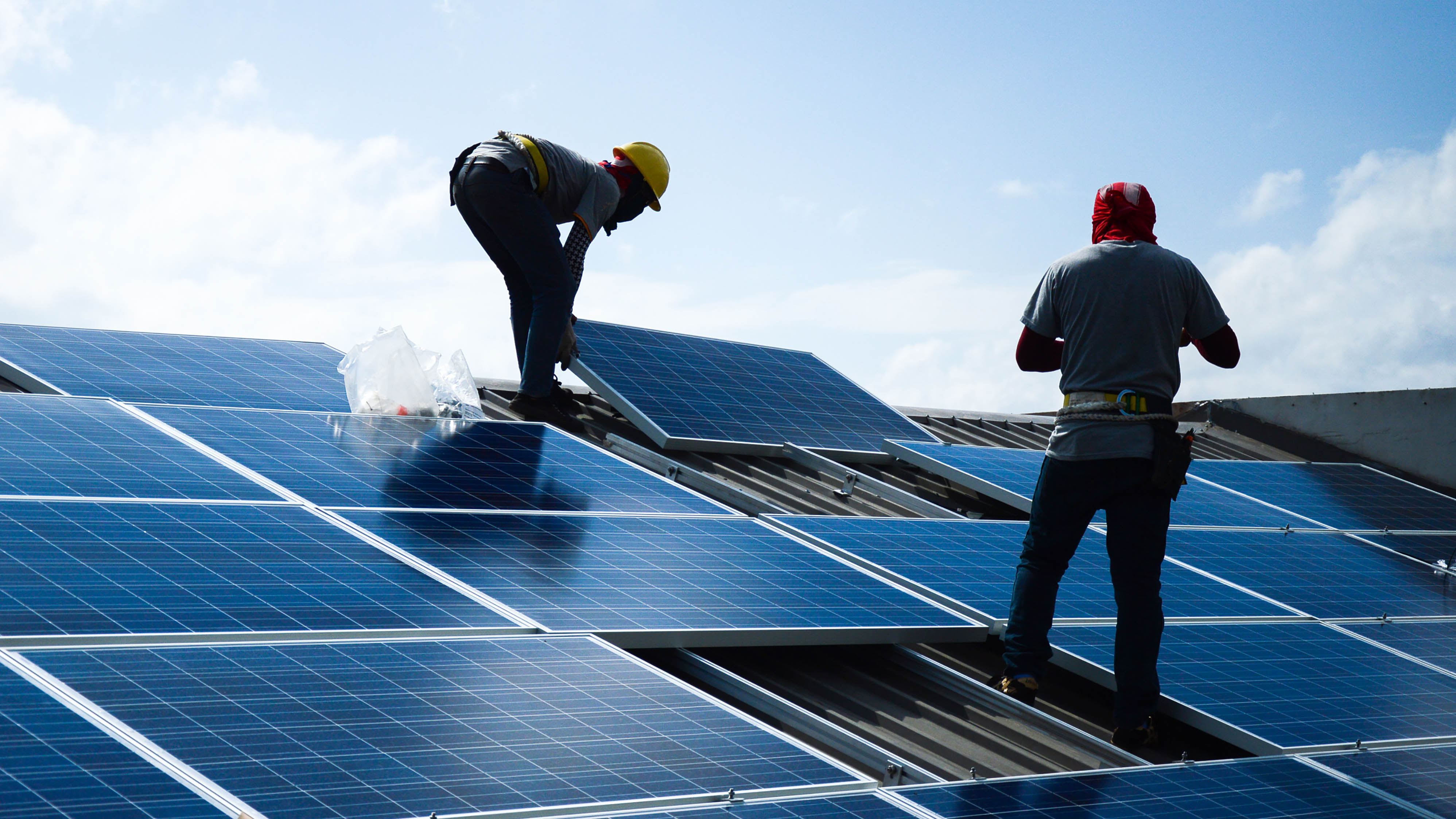 Deux hommes installant des panneaux solaires sur un toit