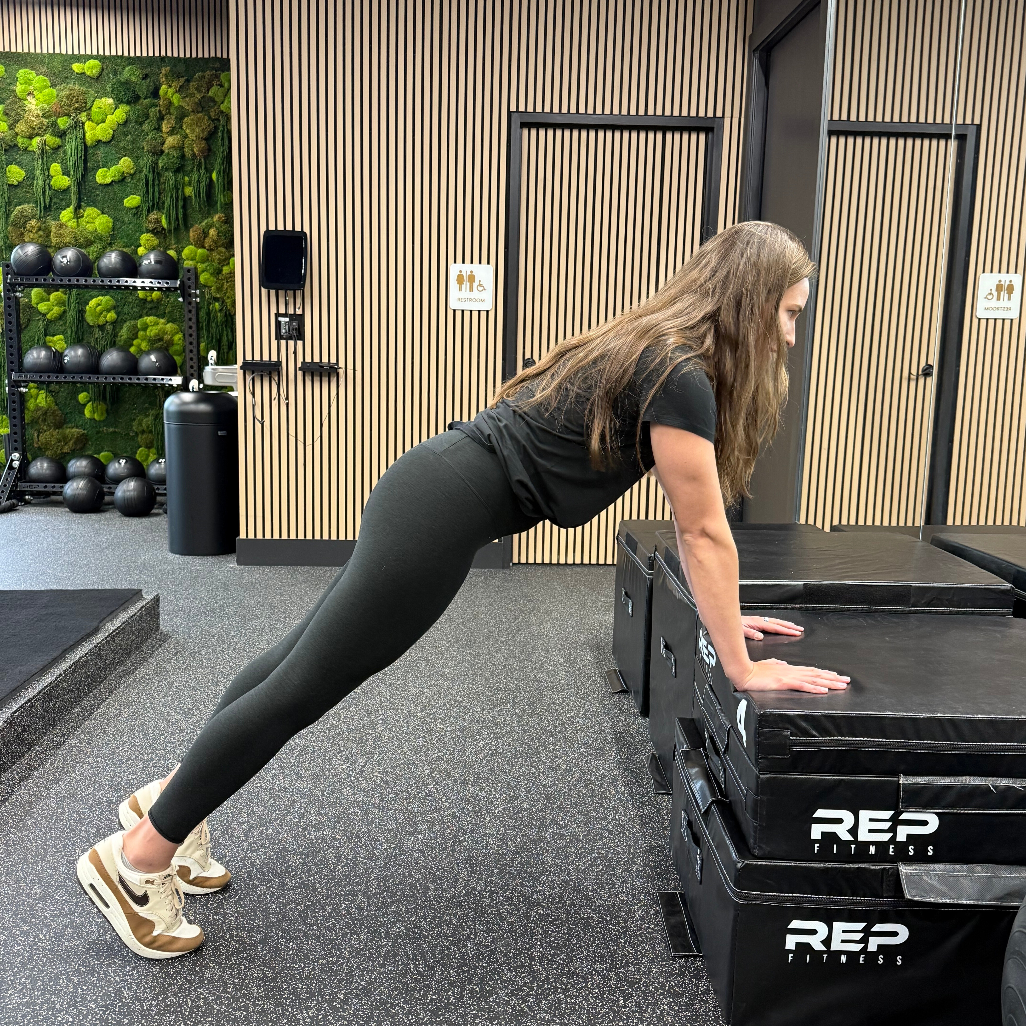 Woman demonstrates exercise in empty gym