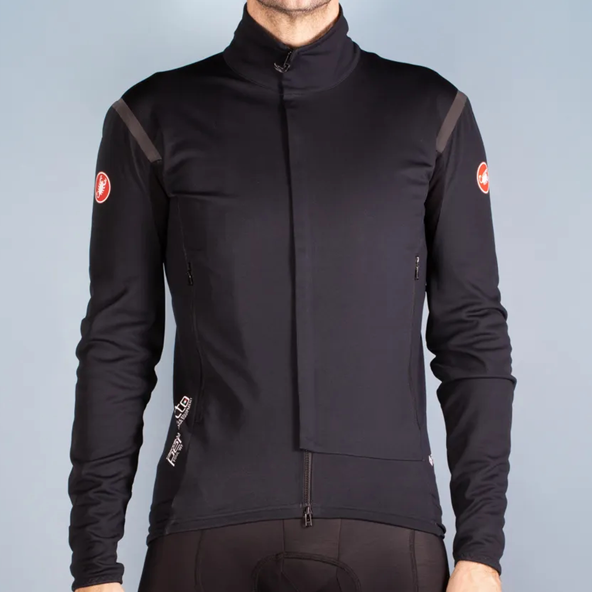 A male model in a black cycling jacket with castelli logos in red on both upper sleeves