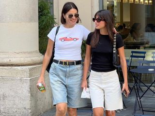 Two women wearing long denim shorts with short-sleeve t-shirts.